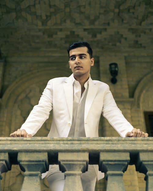 Man in White Suit Posing behind Wall