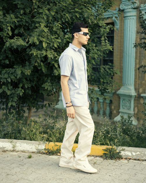 Free Young man walking casually outdoors wearing summer attire and sunglasses. Stock Photo