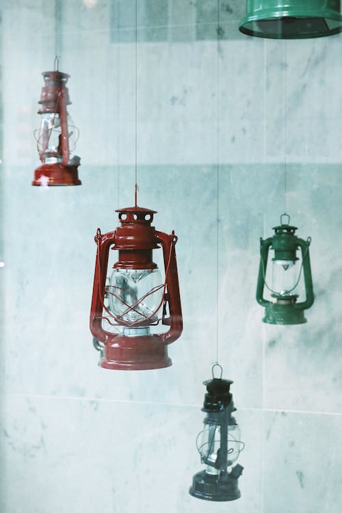 Four Assorted-color Metal Gas Lanterns Hanging Near Tile Wall