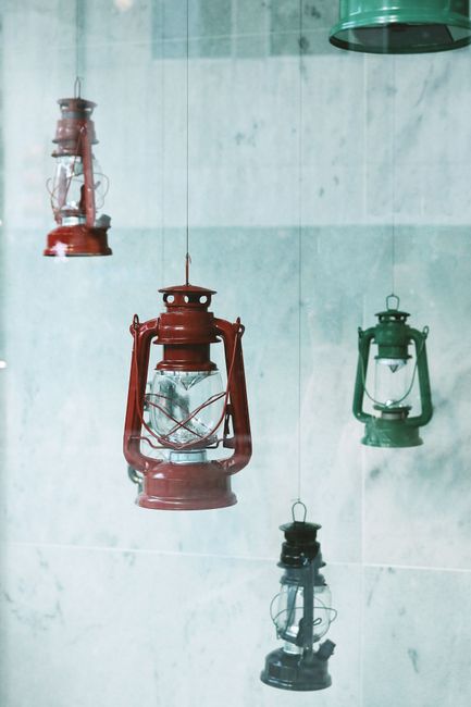 Aesthetic display of colorful vintage lanterns suspended against a marble wall.