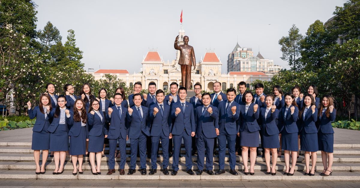 Business professionals posing confidently in front of the Ho Chi Minh statue, Vietnam.