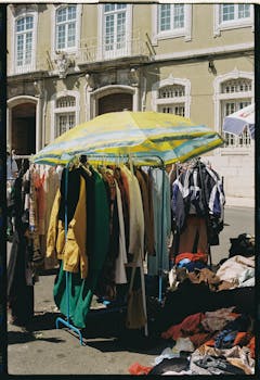 Explore Lisbon's vibrant outdoor markets showcasing colorful clothing stalls under sunny skies.