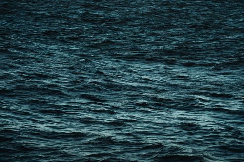 Free A serene view of the ocean's surface showing gentle, dark blue waves. Stock Photo