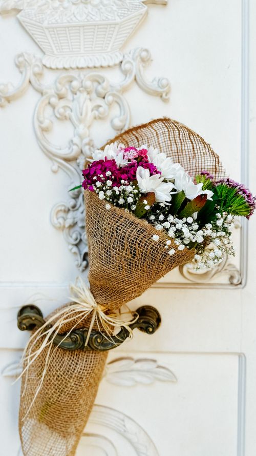 Free A beautifully wrapped flower bouquet hangs on an ornate vintage door. Stock Photo