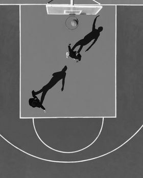 Drone view of an outdoor basketball game with three players casting shadows.