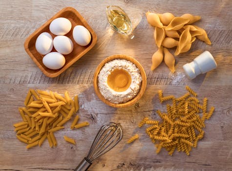 A flat lay of essential ingredients for homemade pasta making, including eggs, flour, and different pasta types.