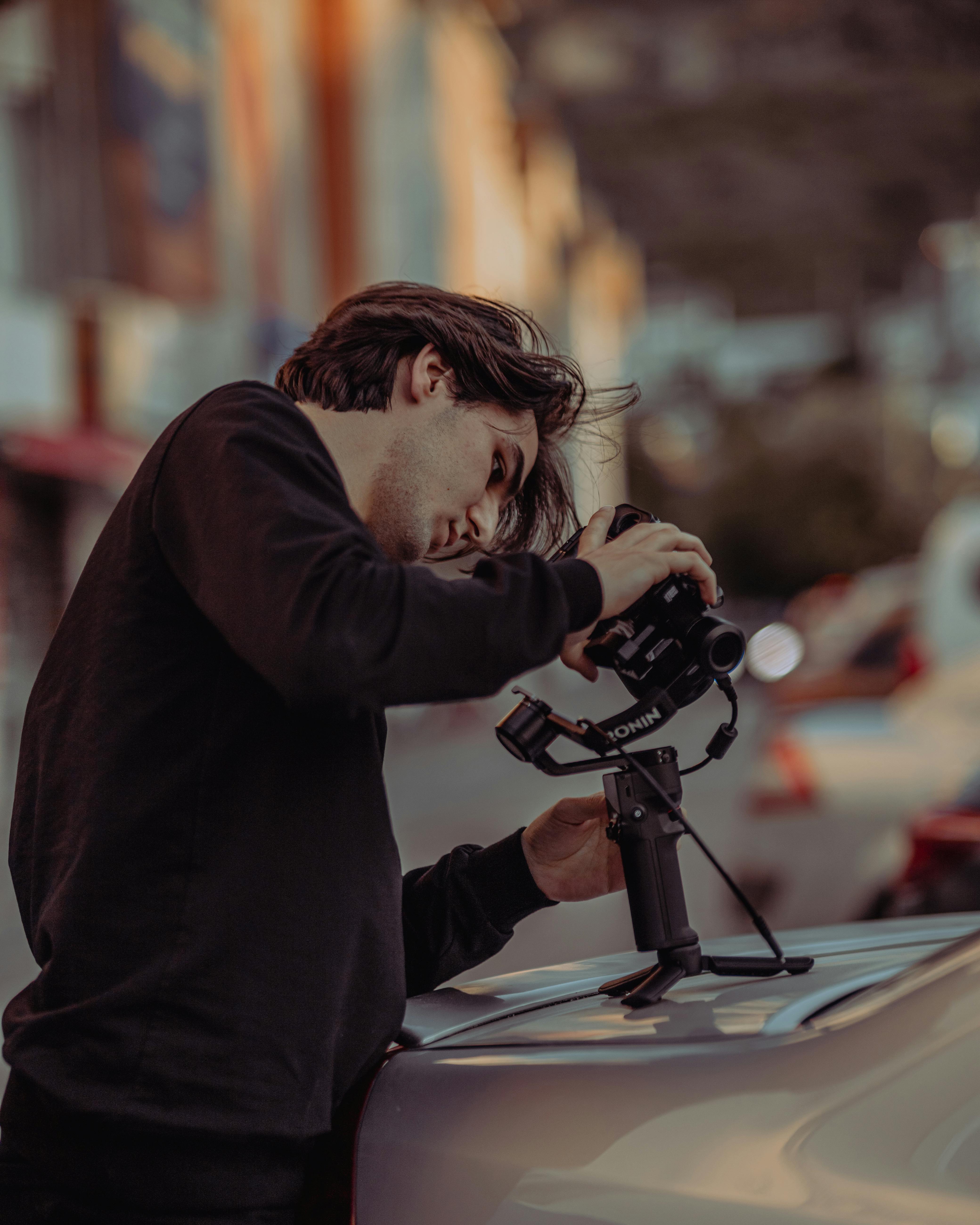 Free A focused young photographer uses a camera gimbal atop a car in urban Fethiye, Türkiye. Stock Photo
