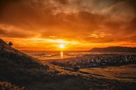 沿海村庄笼罩在令人惊叹的日落中，天空充满活力，绿树成荫