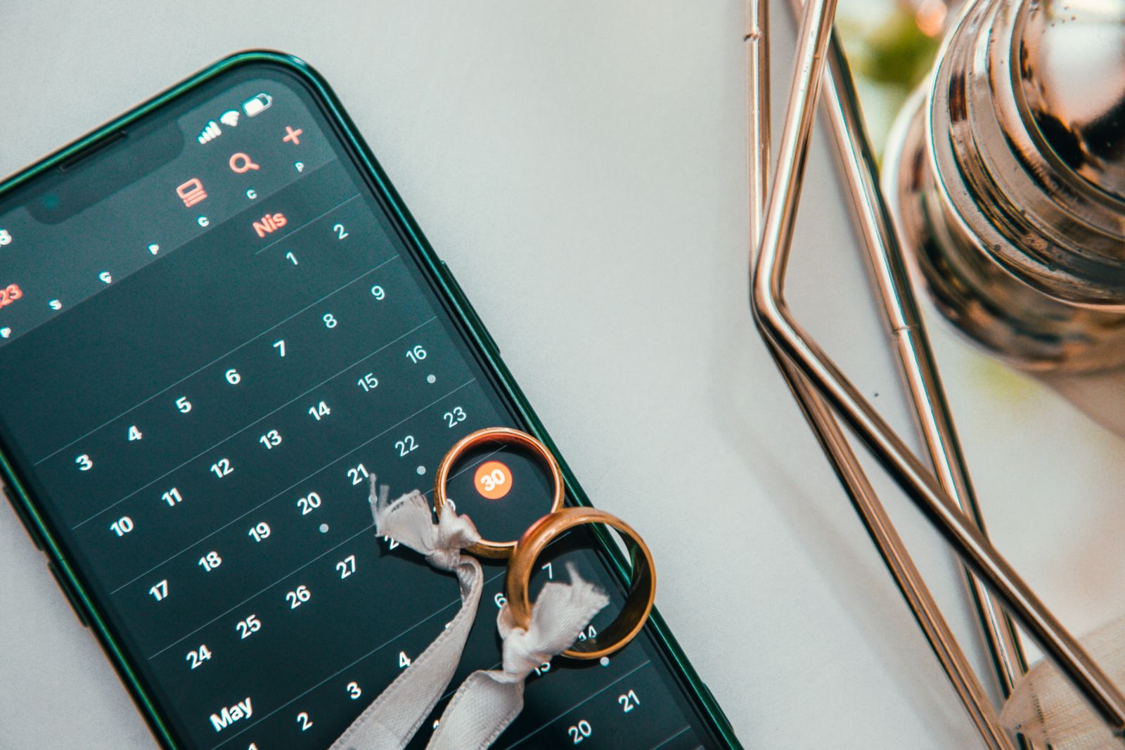 Écran de smartphone affichant une application de suivi d'habitudes avec calendrier coché en vert, posé sur une table de petit-déjeuner