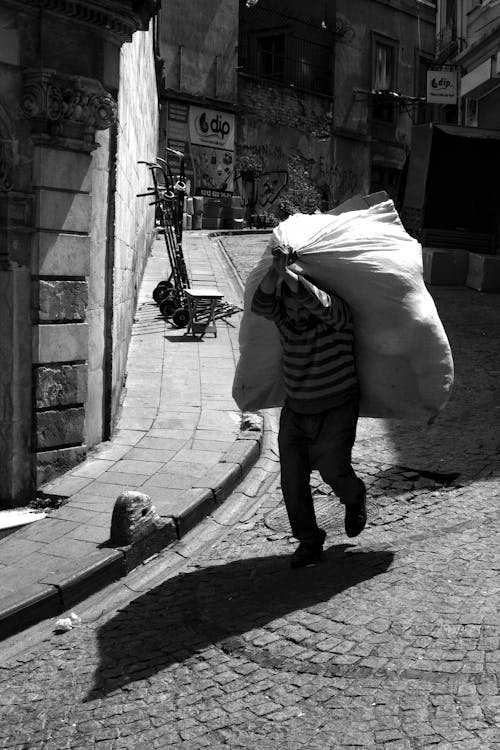 Man Carrying Bag on Street in Black and White