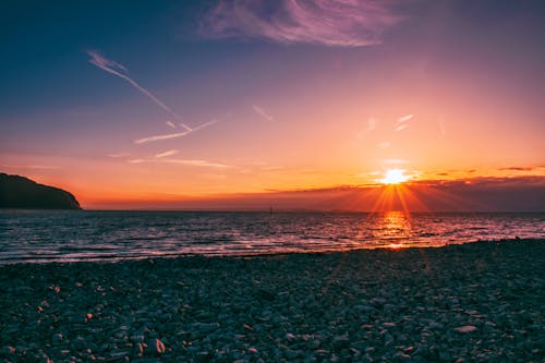 Free Stone Seashore Under Golden Hour Wallpaper Stock Photo