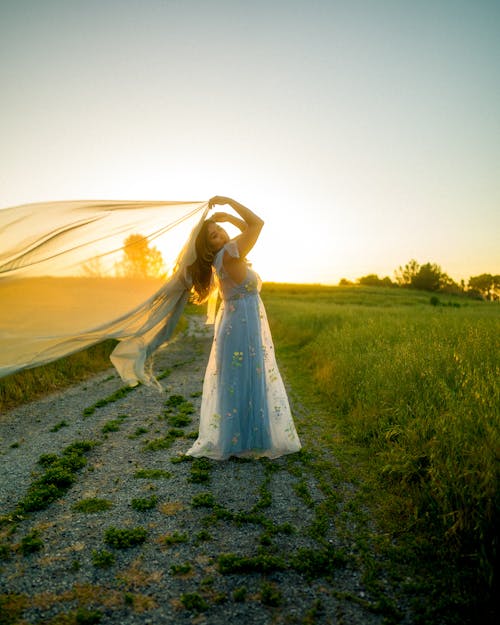 Woman in Dress Posing on Dirt Road at Sunset