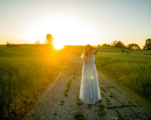 Woman in Dress on Dirt Road at Sunset