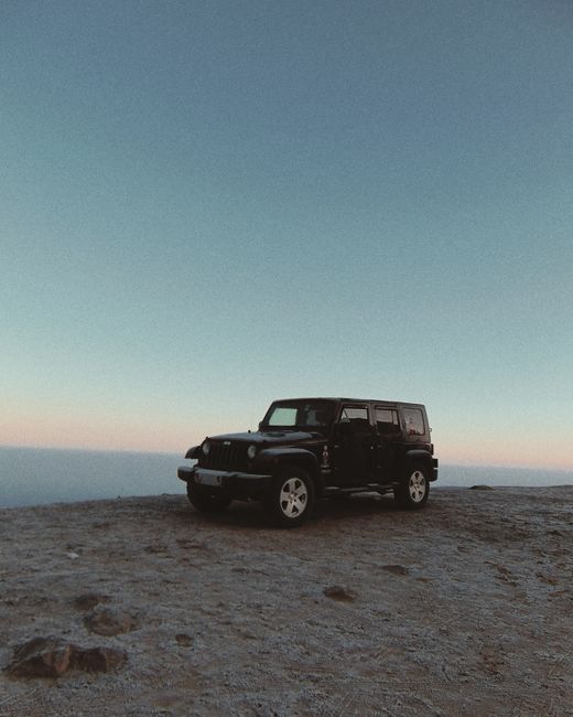 A black Jeep parked on a desert landscape during the early morning light, capturing the essence of adventure.