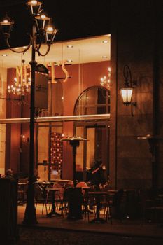 Warmly lit outdoor cafe at night with empty tables, capturing a cozy atmosphere.