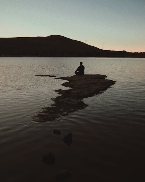無料 海の岩の上に座っている男 写真素材