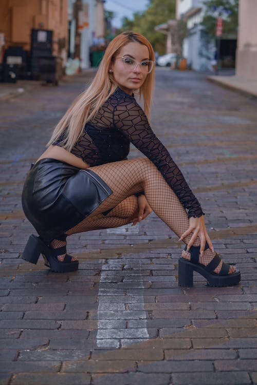 Blonde Woman in Eyeglasses Squatting and Posing on Street