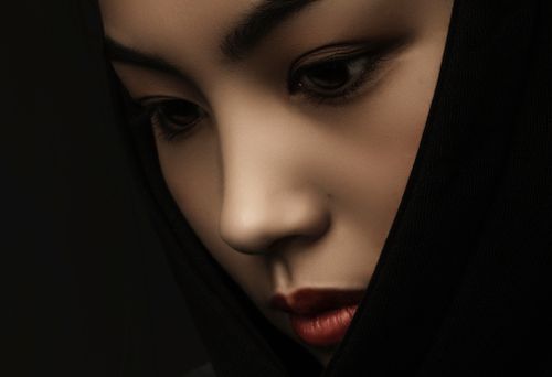 Free Close-up studio portrait of a woman in a headscarf against a dark background, reflecting thoughtfulness. Stock Photo