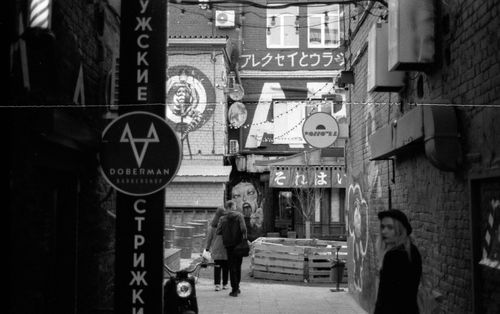 Free Black and white photo of an urban alley filled with street art and diverse signage. Stock Photo