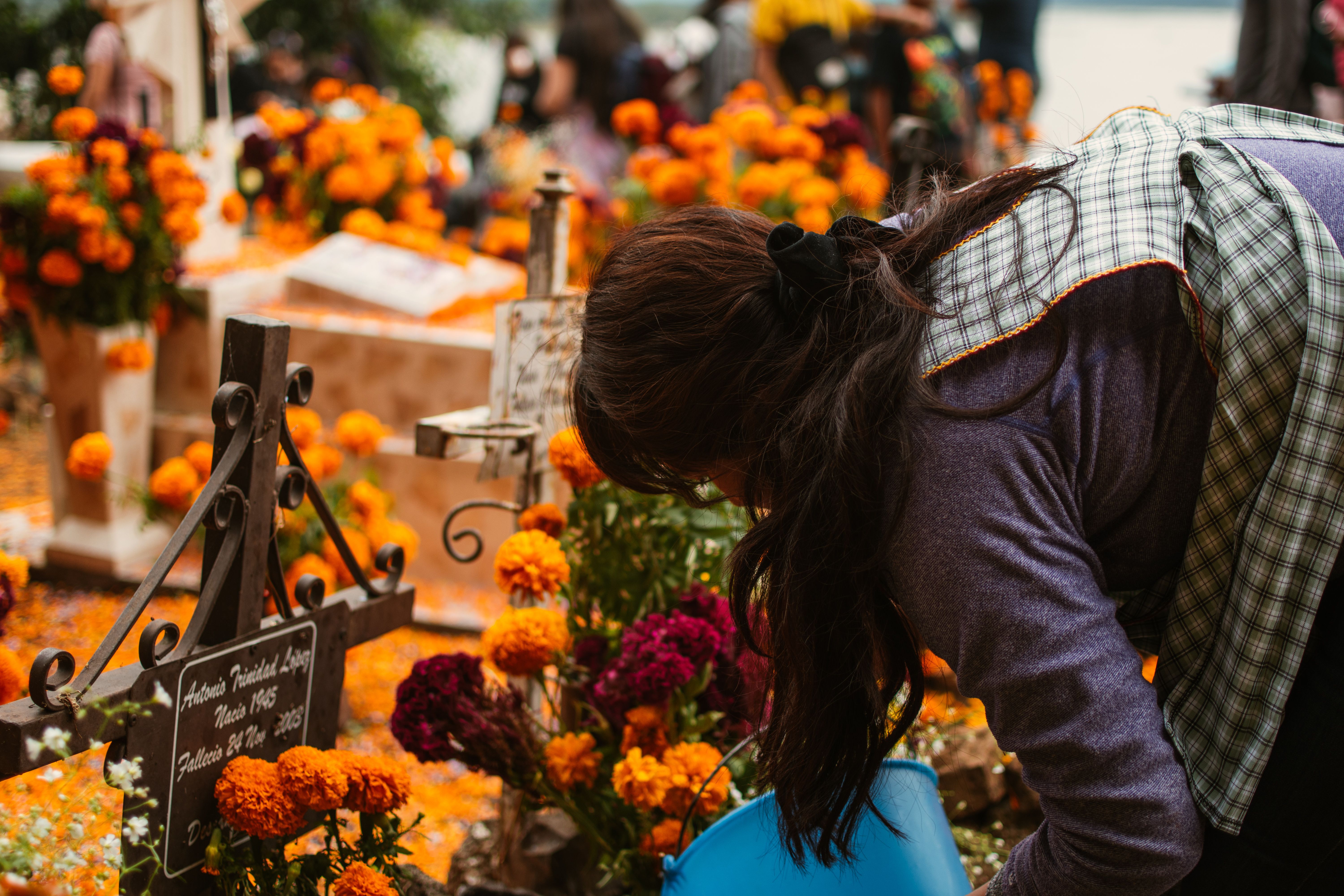 A woman tends to a grave adorned with vibrant marigolds during Día de Muertos in Janitzio, Mexico.
