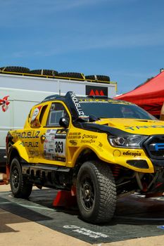 Dynamic yellow rally car ready for race day action under the clear sky.