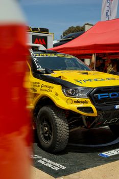 Yellow Ford racing truck with distinctive livery on display at an outdoor car event.