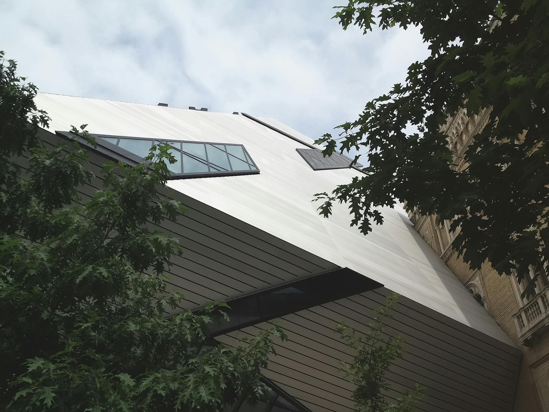 Low angle view of a modern building in Toronto surrounded by trees.