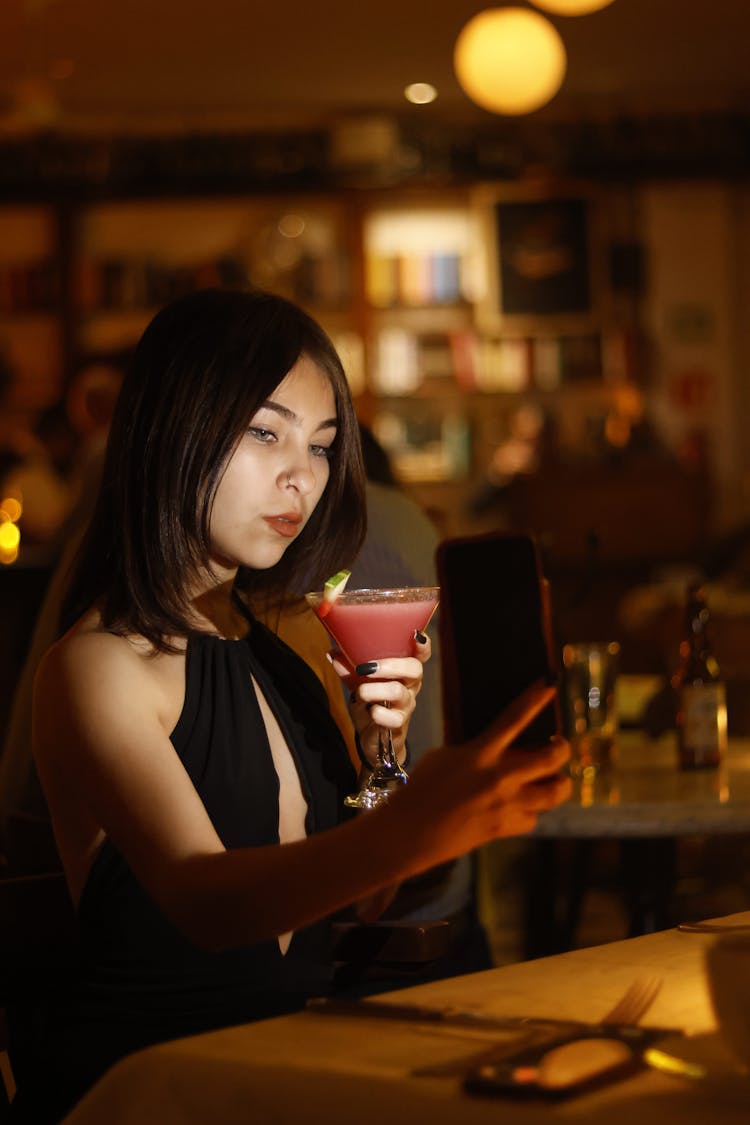 Woman Taking Selfie With Cocktail In Bar