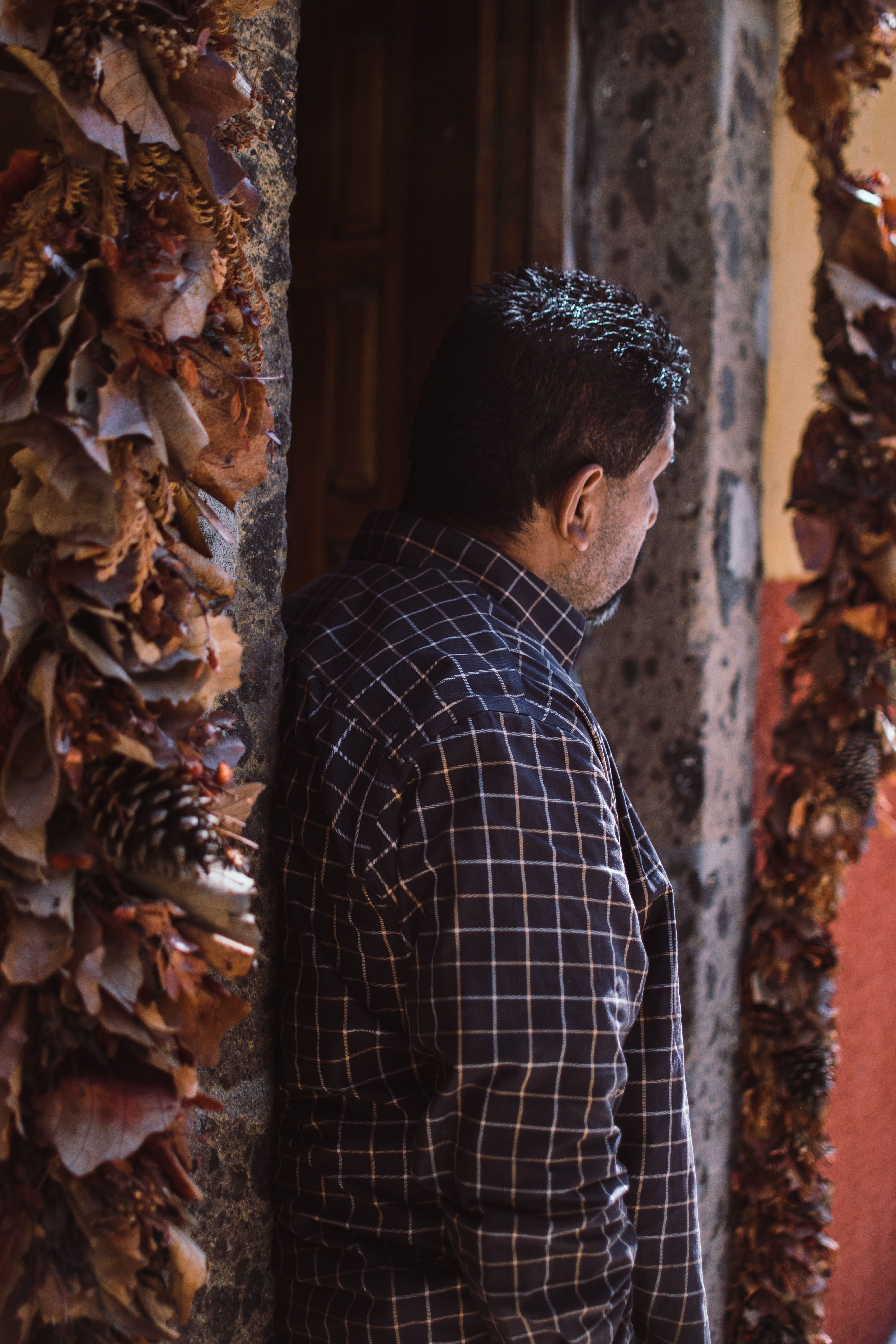 A man in a checkered shirt stands near a decorated archway in San Miguel de Allende, Mexico.