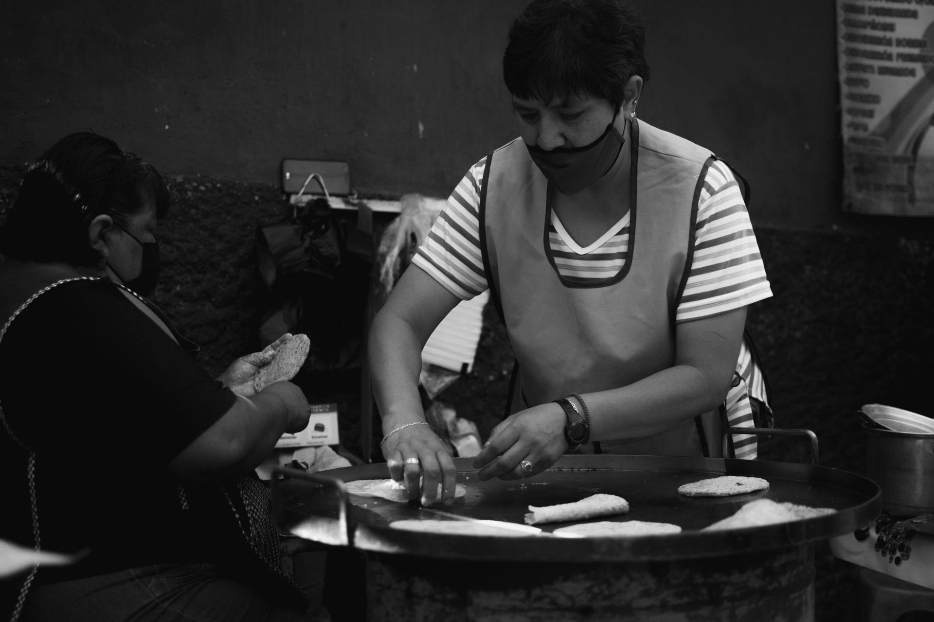 Two women prepare traditional Mexican street food in Guanajuato, capturing cultural culinary art.