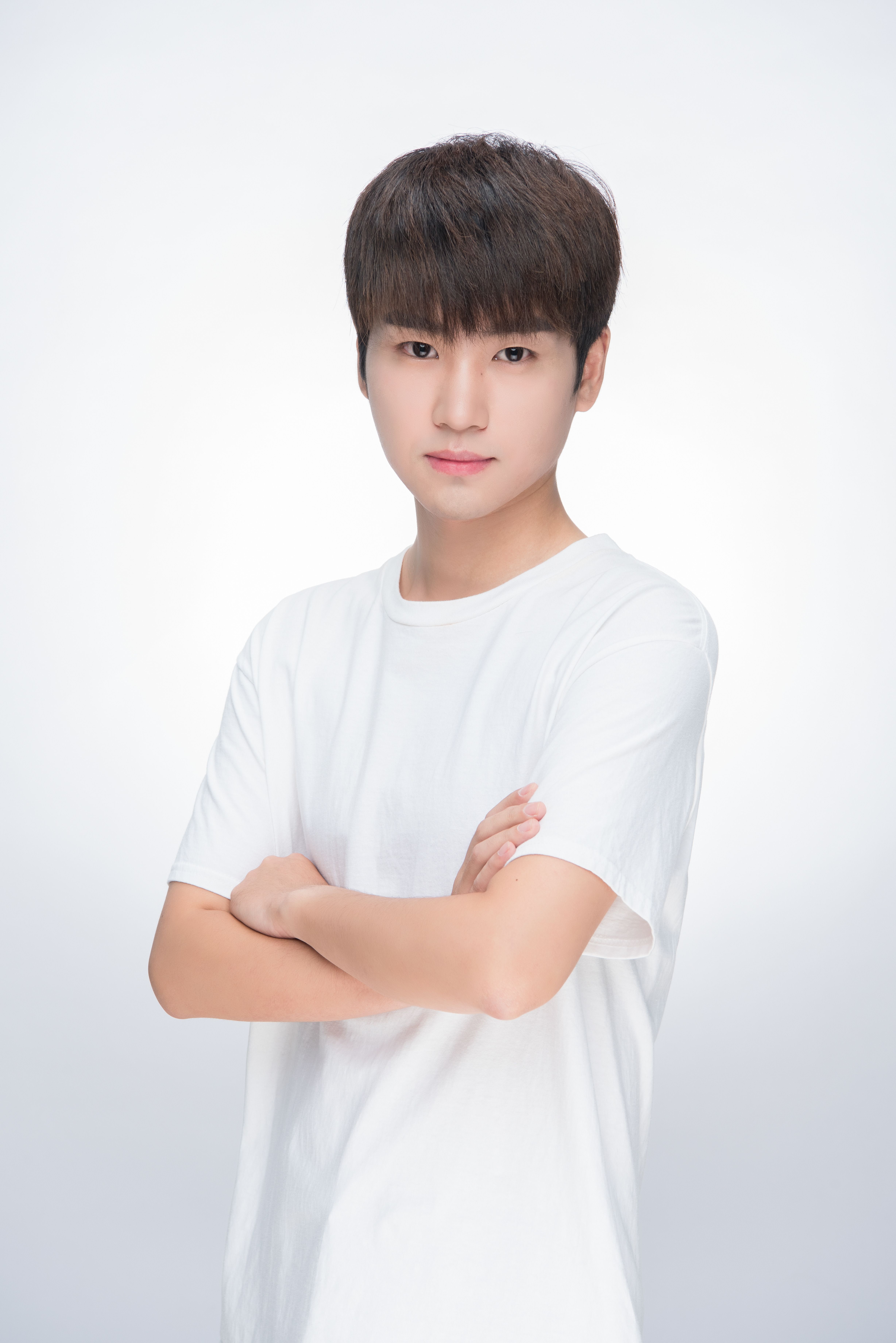 Portrait of a confident teenage boy wearing a white t-shirt, standing in a studio setting.
