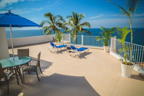 Free Blue Loungers on Beige Balcony Beside Sea Landscape Photography Stock Photo