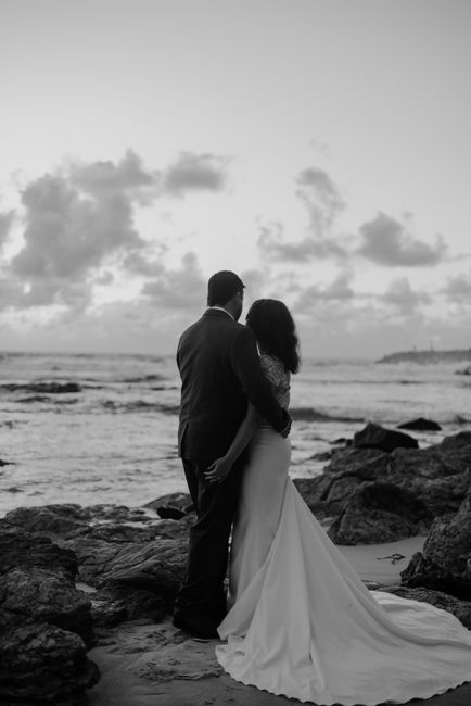 Newlyweds embracing on Byron Bay beach in a black and white photo.
