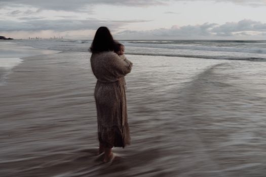 A woman walking on the beach with her child