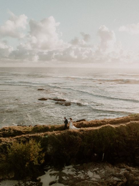 A couple walks hand in hand by the sea, capturing a serene and romantic moment at sunset.