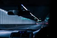 一辆汽车在夜间驶过灯火通明的城市隧道，展现了现代交通的内部视角