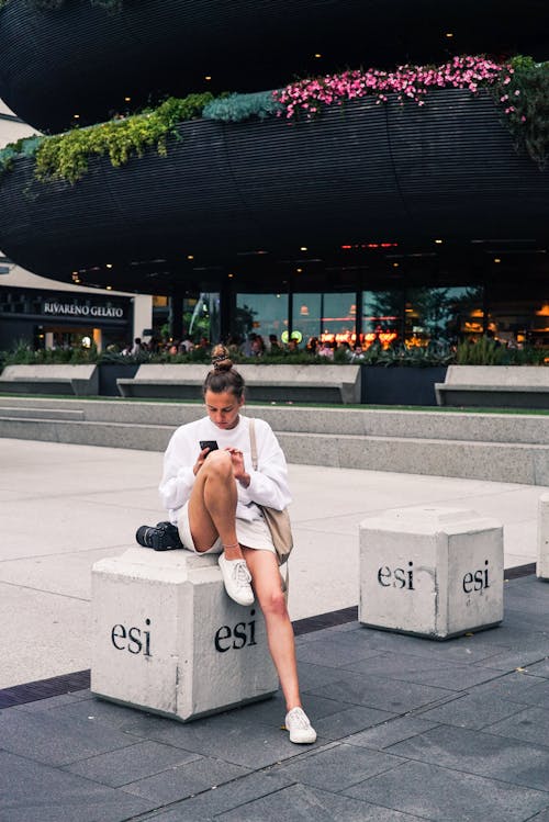 Woman Sitting on Concrete Barrier in Park