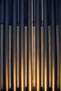 一张精致的抽象照片中，垂直的金属管被金色灯光照亮