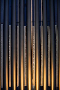 一张精致的抽象照片中，垂直的金属管被金色灯光照亮