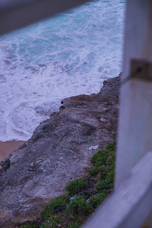 無料 ビーチの波の横にある灰色の岩の崖 写真素材