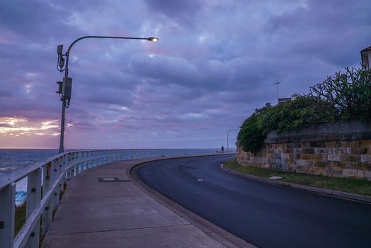 黄昏时分，一条宁静的沿海道路在阴沉的天空下延伸，还能看到海景