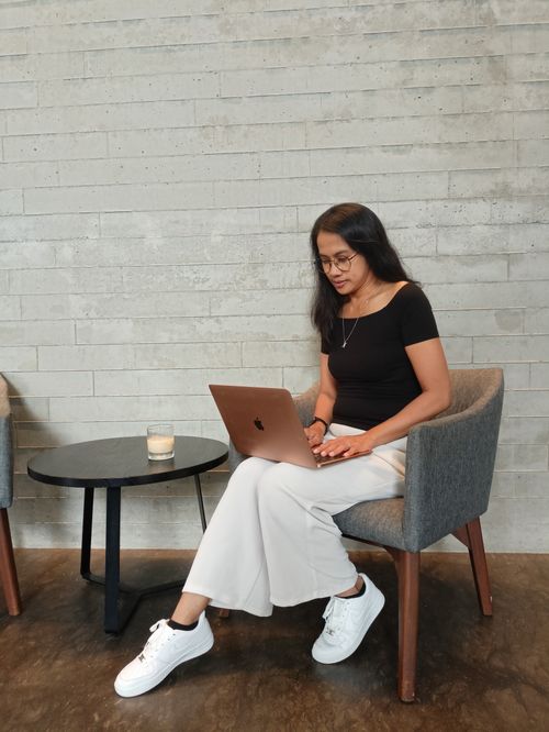 Free Young woman with long hair writing on laptop in a Jakarta cafe setting, embracing productivity. Stock Photo