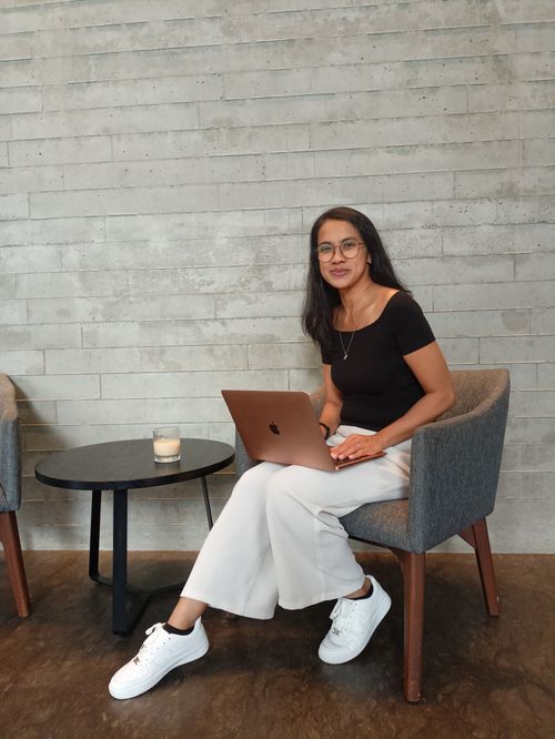 Free Woman sitting in a café with a laptop, casual attire, relaxed work environment. Stock Photo