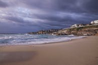 风景优美的海滩上，海浪汹涌，头顶乌云密布，呈现出一派令人惊叹的沿海景观