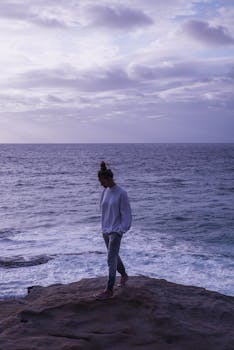宁静的夜晚，一位孤独的女人沿着海边的岩石海岸散步