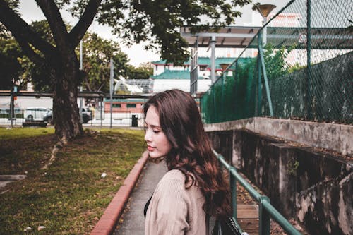 Mujer Vistiendo Cárdigan Marrón Caminando En El Parque Cerca De Un árbol Verde