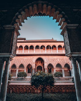 Captivating view through arches of Real Alcázar courtyard, Seville, showcasing Moorish architecture.