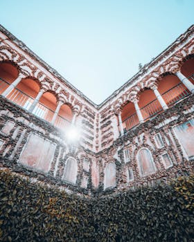 Low-angle view of a beautiful courtyard in Seville, showcasing intricate colonnades and sunlight.