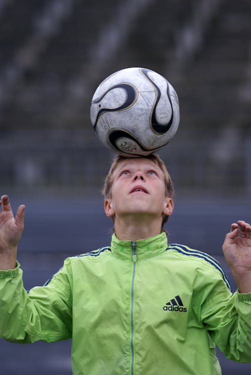 A young boy balancing a soccer ball on his head