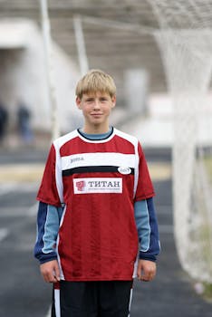 Young soccer player in team uniform standing on the field, ready for the game.